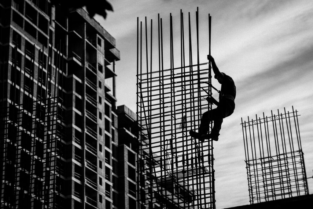 Construction worker unsafely standing on reinforcing bars while working at height without fall protection.