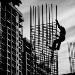 Construction worker unsafely standing on reinforcing bars while working at height without fall protection.
